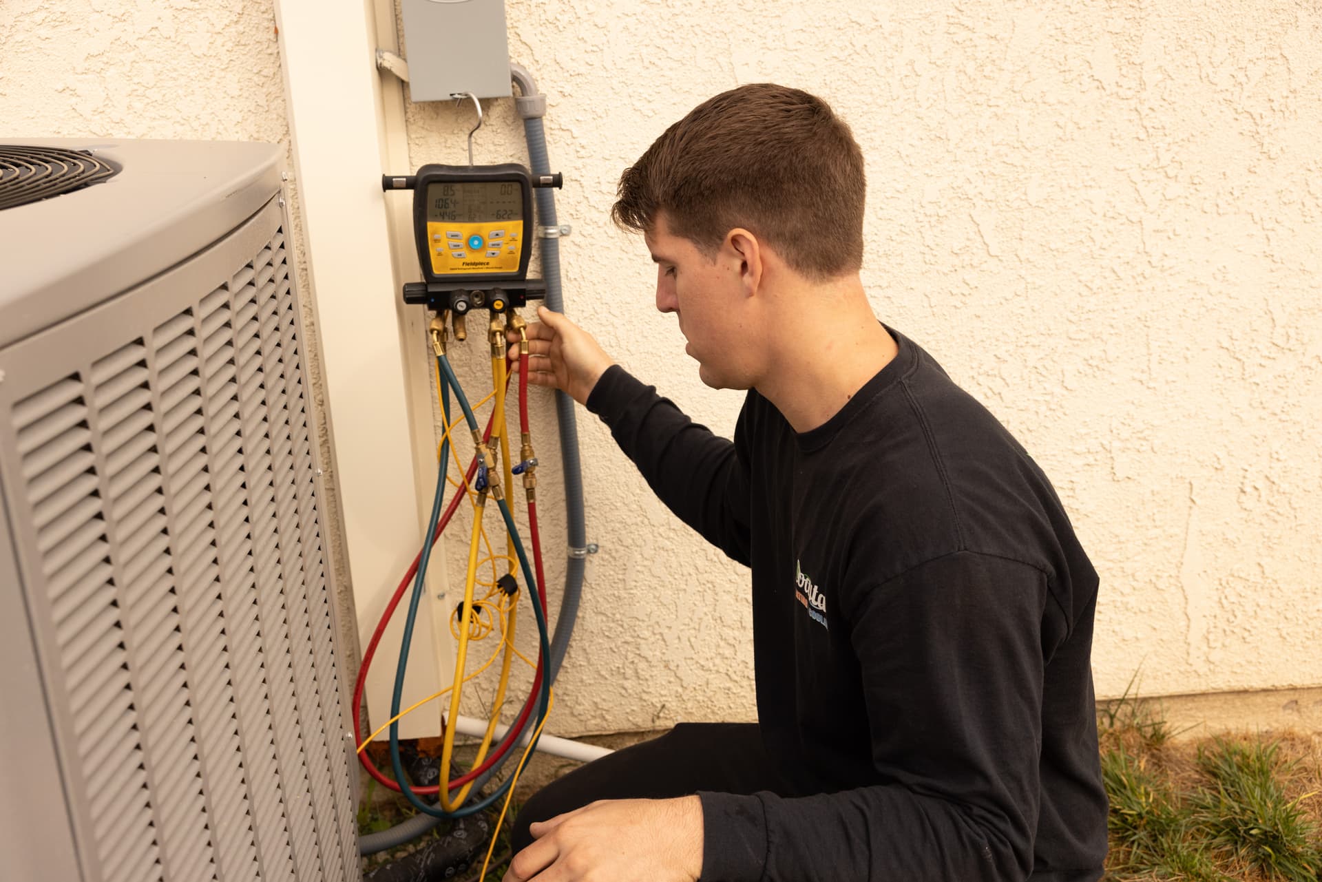 A Coastal HVAC technician servicing an outdoor AC unit.